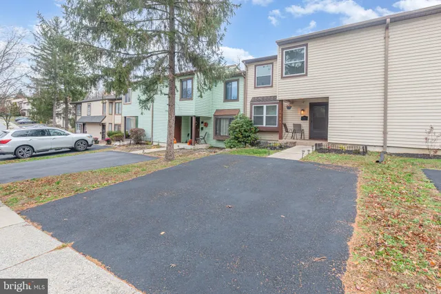 a backyard of a house with large trees and plants