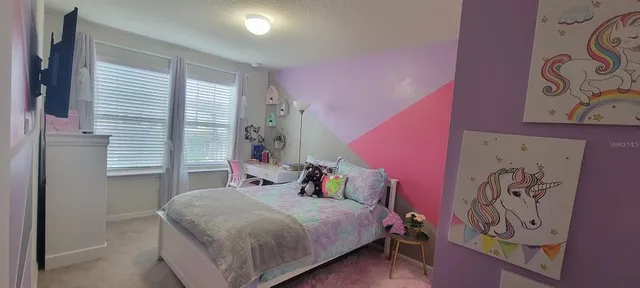 a bedroom with a bed and a flat tv screen on the dresser