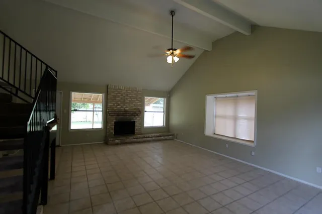 an empty room with windows fireplace and fans