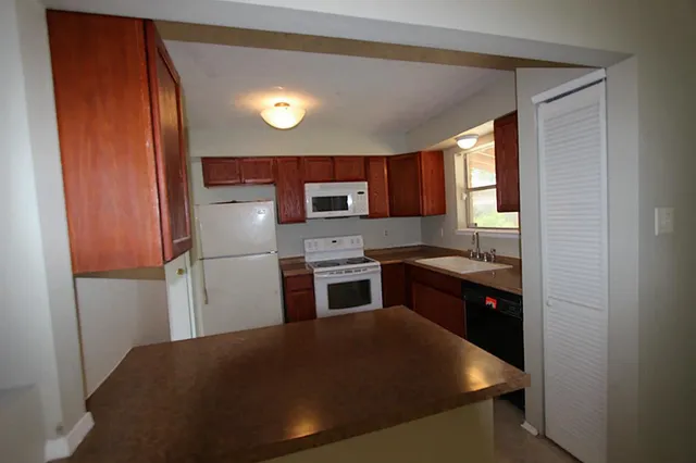 a kitchen with stainless steel appliances granite countertop a refrigerator a stove a sink and a microwave