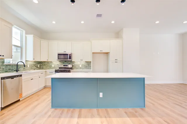 a kitchen with stainless steel appliances a sink stove and cabinets