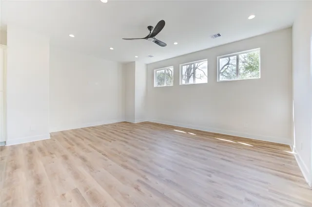 a view of empty room with wooden floor and fan