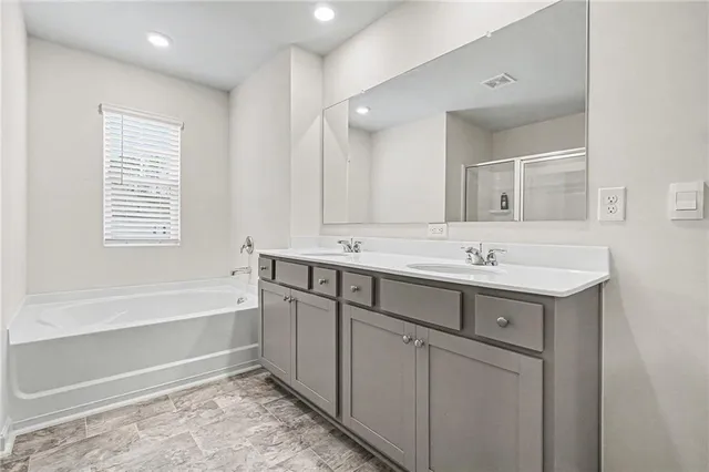 a bathroom with a sink double vanity mirror and a bathtub
