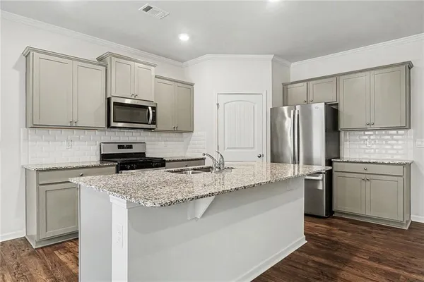 a kitchen with kitchen island granite countertop appliances cabinets and a counter space