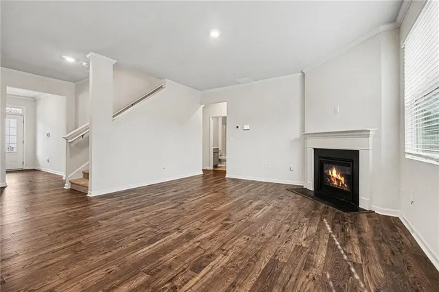 a view of an empty room with wooden floor fireplace and a window