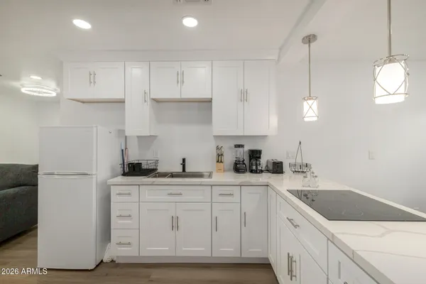 a kitchen with a sink dishwasher and white cabinets with wooden floor