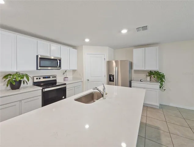 a kitchen with granite countertop a refrigerator stove microwave and sink