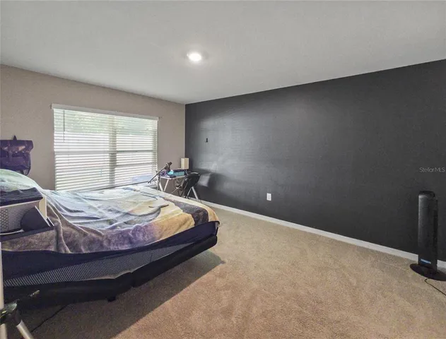 a bed sitting in a spacious bedroom next to a window