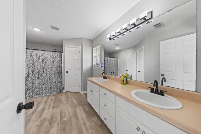 a spacious bathroom with a double vanity sink a mirror and shower