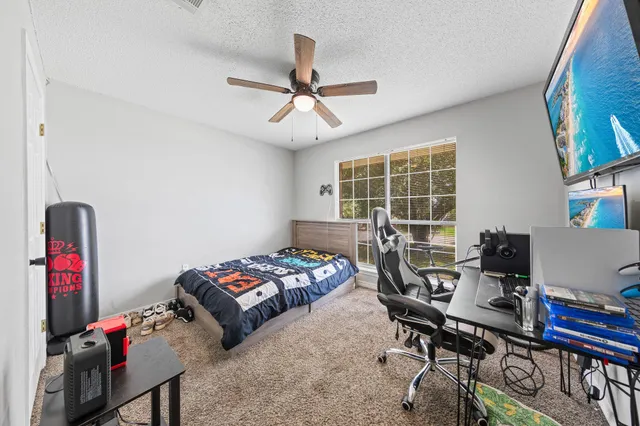 a bedroom with a bed a desk and chair with window