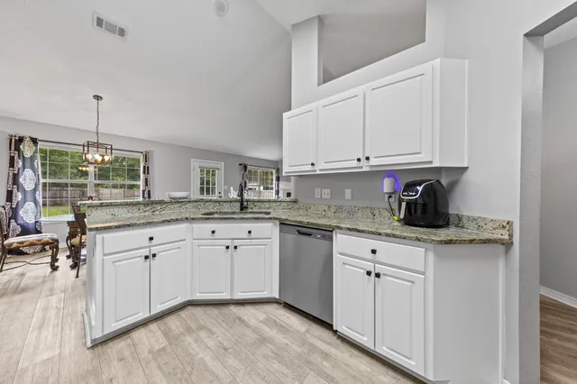 a kitchen with granite countertop white cabinets white appliances and sink