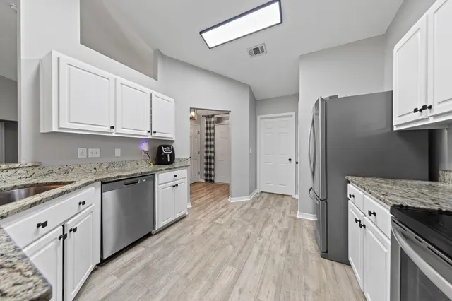 a kitchen with granite countertop a refrigerator stove top oven and sink