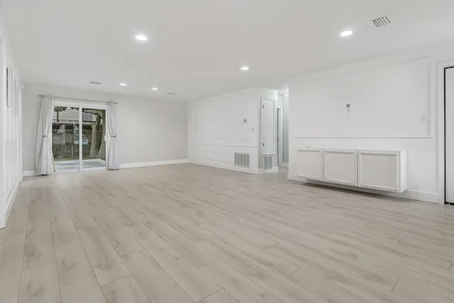 a view of a refrigerator in kitchen and an empty room