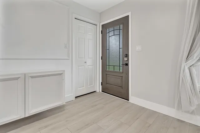 an empty room with wooden floor cabinet and windows