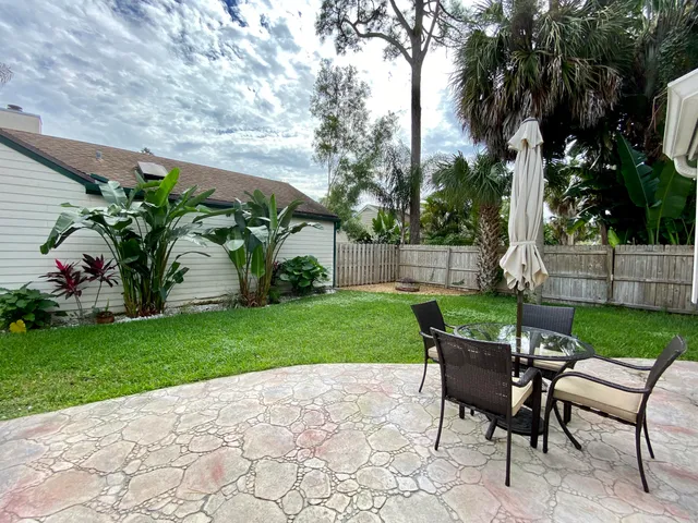 a view of a backyard with table and chairs potted plants and tree