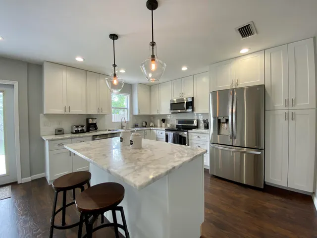 a kitchen with refrigerator a sink and chairs