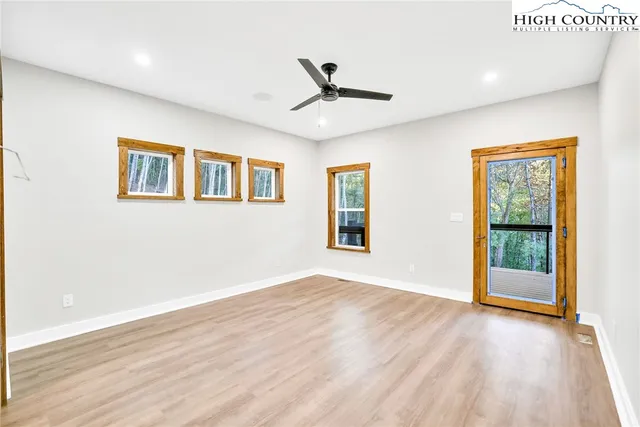 a view of an empty room with a window and wooden floor