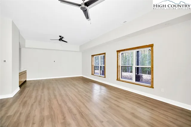 an empty room with wooden floor cabinet and windows