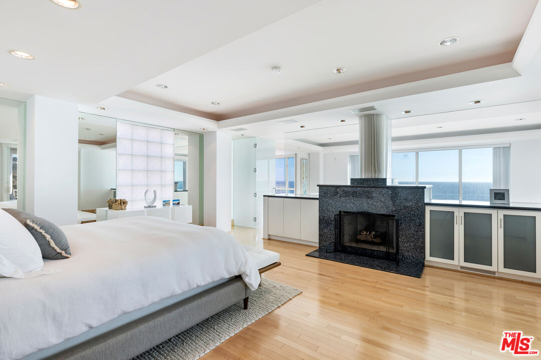 32062 Pacific Coast Highway Malibu, CA 90265 - Photo 12 of 31 a bedroom with a large bed and a fireplace