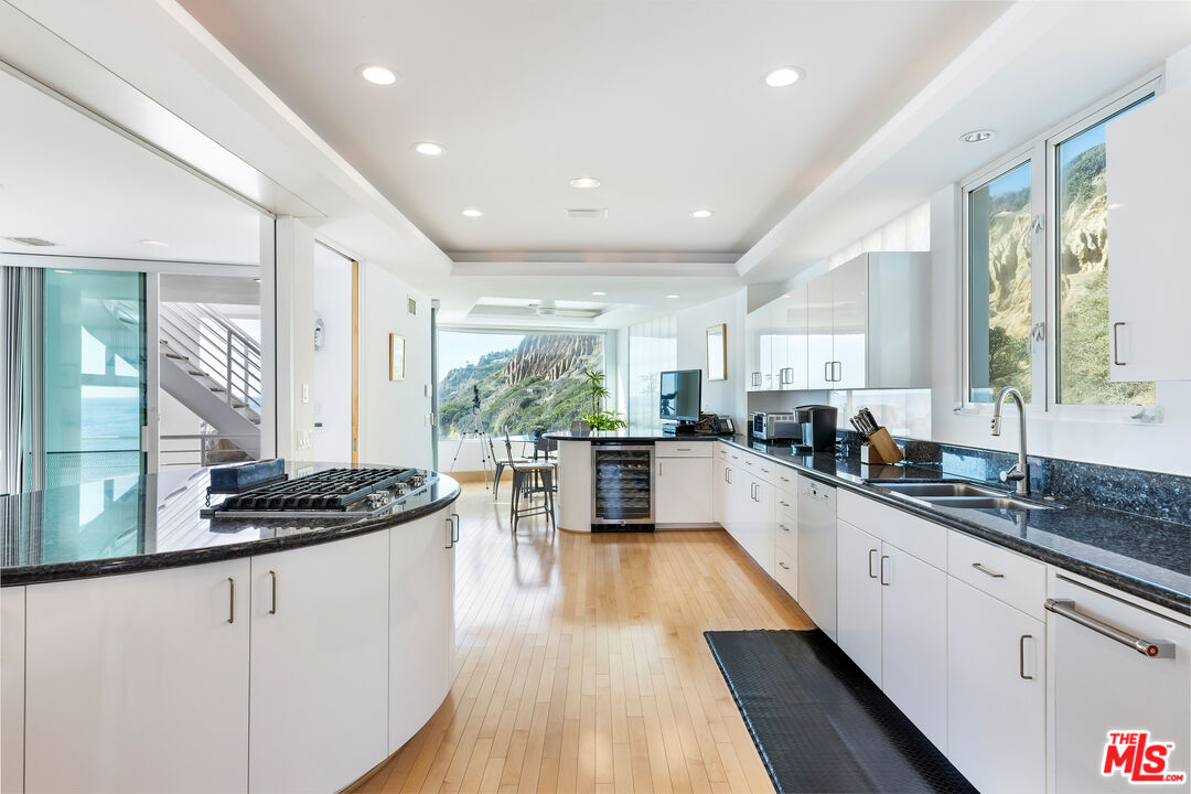 32062 Pacific Coast Highway Malibu, CA 90265 - Photo 15 of 31 a kitchen with stainless steel appliances kitchen island granite countertop a stove a sink and white cabinets with wooden floor