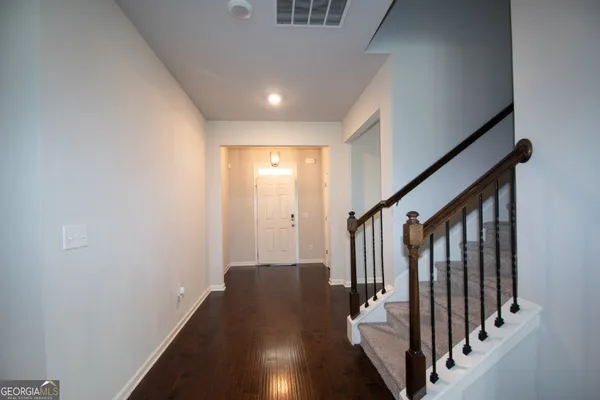 an entryway in a hall with wooden floor and stairs