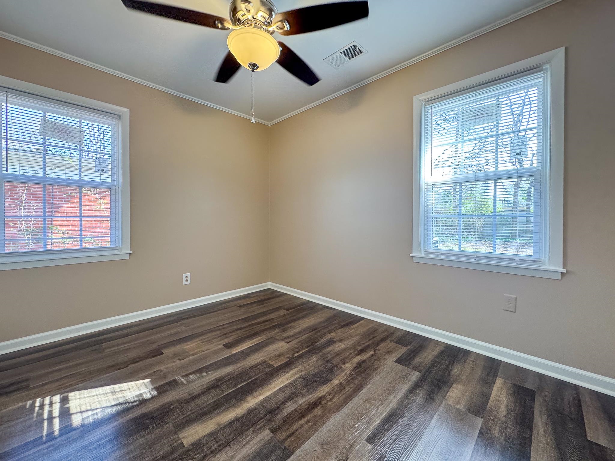 842 Rock Road Memphis, TN 38122 - Photo 15 of 26 Spare room with visible vents, plenty of natural light, dark wood-type flooring, and crown molding
