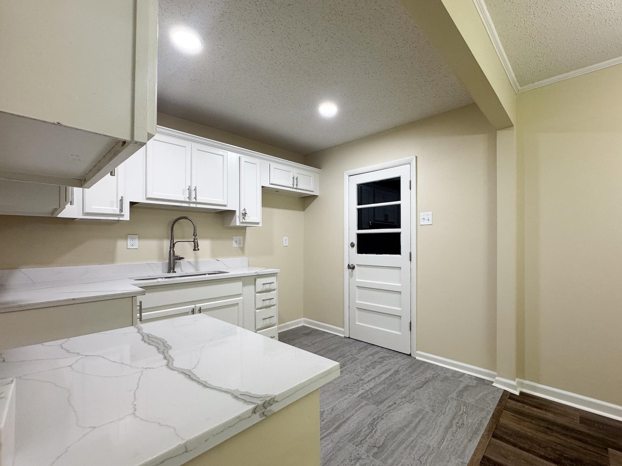 842 Rock Road Memphis, TN 38122 - Photo 8 of 26 Kitchen featuring a sink, wood finished floors, white cabinetry, baseboards, and light stone countertops