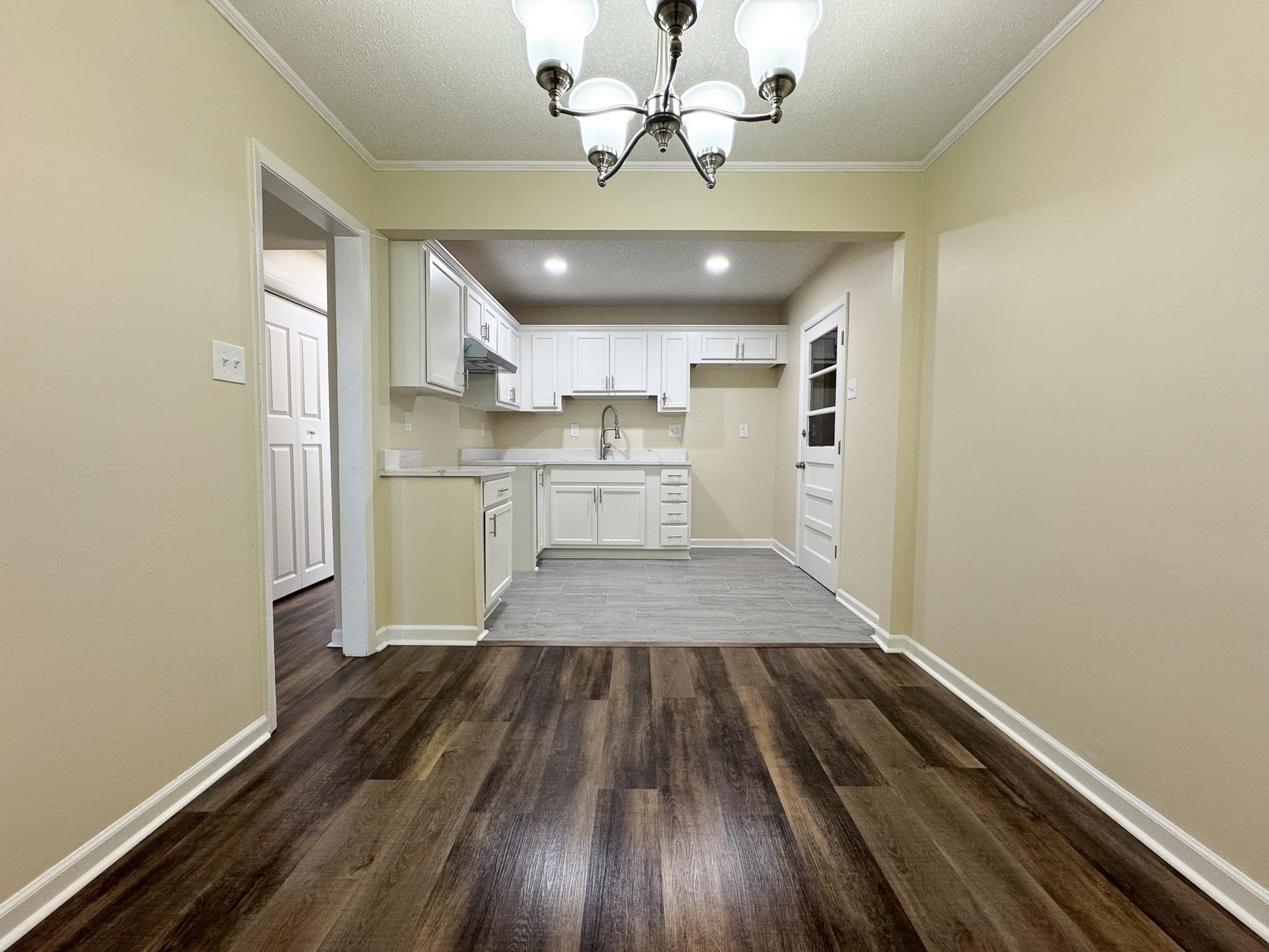 842 Rock Road Memphis, TN 38122 - Photo 9 of 26 Kitchen with dark wood-style floors, a sink, light countertops, white cabinetry, and a notable chandelier