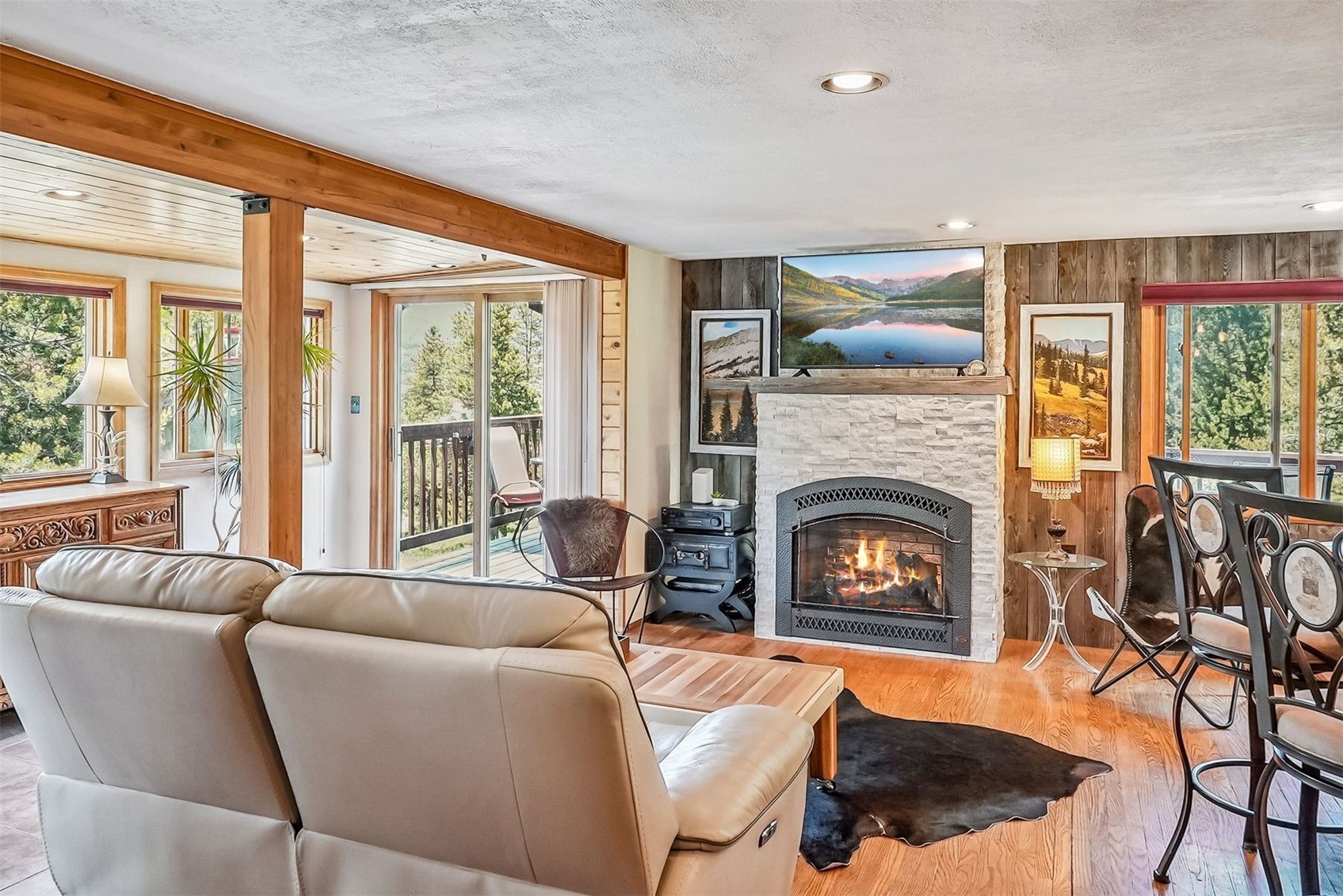 57 L Road Silverthorne, CO 80498 - Photo 4 of 38 Living room with a stone fireplace, wooden walls, and a wealth of natural light