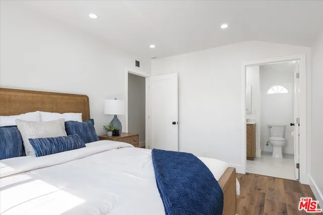 a bedroom with a large bed and wooden floor