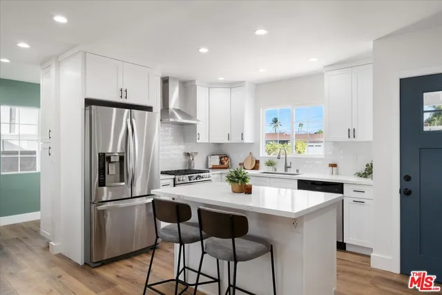 a kitchen with a refrigerator a stove a sink and white cabinets with wooden floor