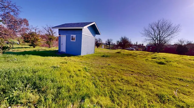 an aerial view of residential houses with outdoor space and trees