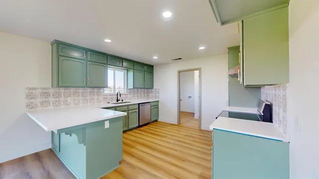 a kitchen with a sink and a stove top oven with wooden floor