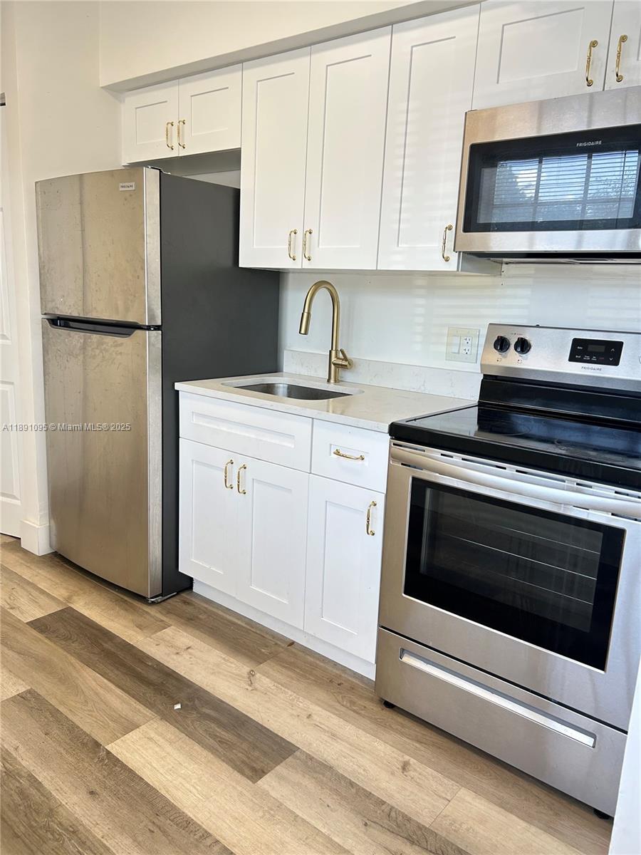 571 Northeast 67th Street, Unit 1 Miami, FL 33138 - Photo 3 of 13 a kitchen with granite countertop white cabinets and stainless steel appliances