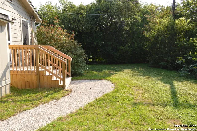 a view of a yard with plants and wooden fence