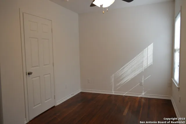 an empty room with wooden floor cabinet and windows