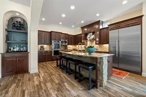 a kitchen with stainless steel appliances granite countertop a refrigerator a stove and a sink with wooden floor