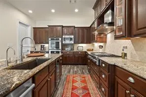 a kitchen with kitchen island granite countertop a sink appliances cabinets and a counter top space