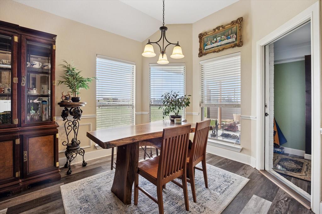 119 George Owens Road Ponder, TX 76259 - Photo 13 of 26 Dining area featuring wood-finish flooring, a contemporary chandelier, and multiple windows with horizontal blinds