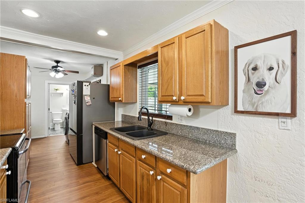 1423 Charles Road Fort Myers, FL 33919 - Photo 10 of 26 Kitchen featuring stainless steel appliances, crown molding, a textured wall, a ceiling fan, and light wood-style floors