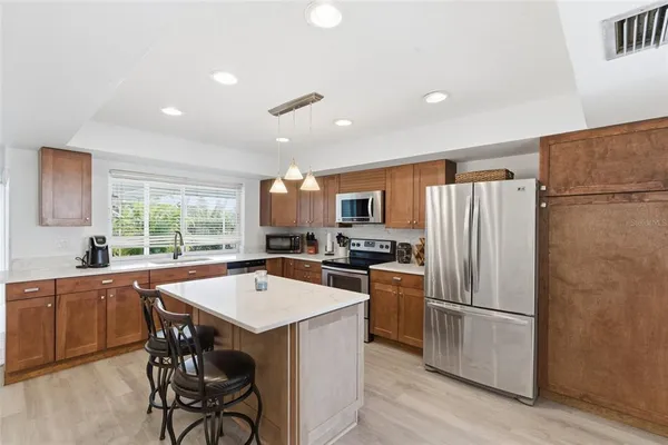 a kitchen that has a refrigerator a sink a stove and chairs