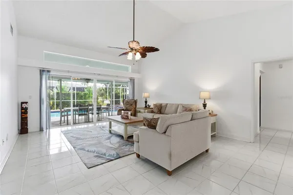 a living room with furniture large window and ceiling fan