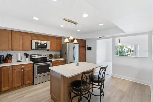 a kitchen with stainless steel appliances granite countertop a kitchen island hardwood floor sink stove dining table and chairs