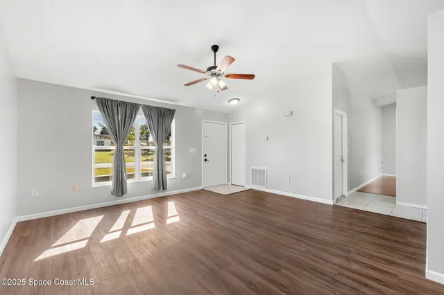 a view of an empty room with wooden floor and a window