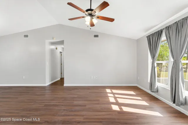 a view of an empty room with window and wooden floor