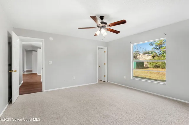 an empty room with windows and fan