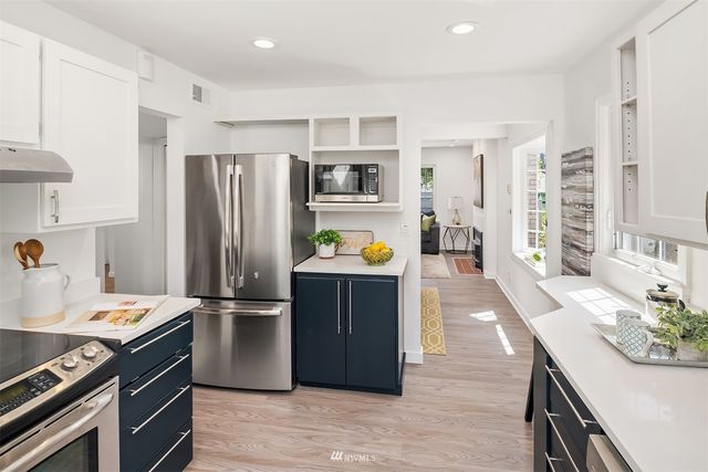 a kitchen with stainless steel appliances granite countertop a refrigerator a stove and a sink with wooden floor