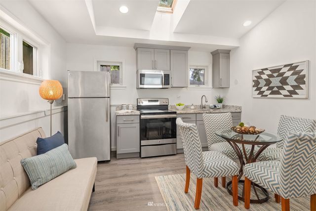 a kitchen with stainless steel appliances granite countertop a stove a sink dishwasher and a refrigerator with wooden floor