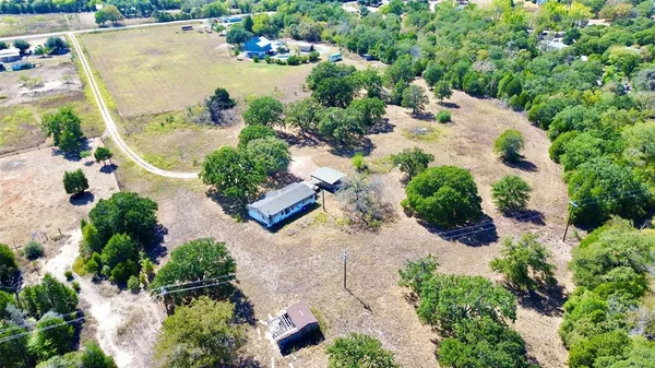 an aerial view of a house with a yard and trees all around