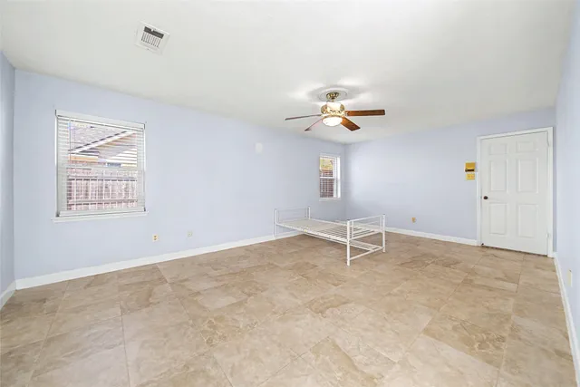an empty room with windows and ceiling fan